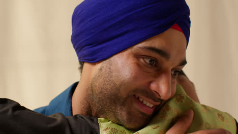 Close-Up-Studio-Shot-Of-Sikh-Father-Embracing-Son-Both-Wearing-Turbans-Against-Plain-Background-3